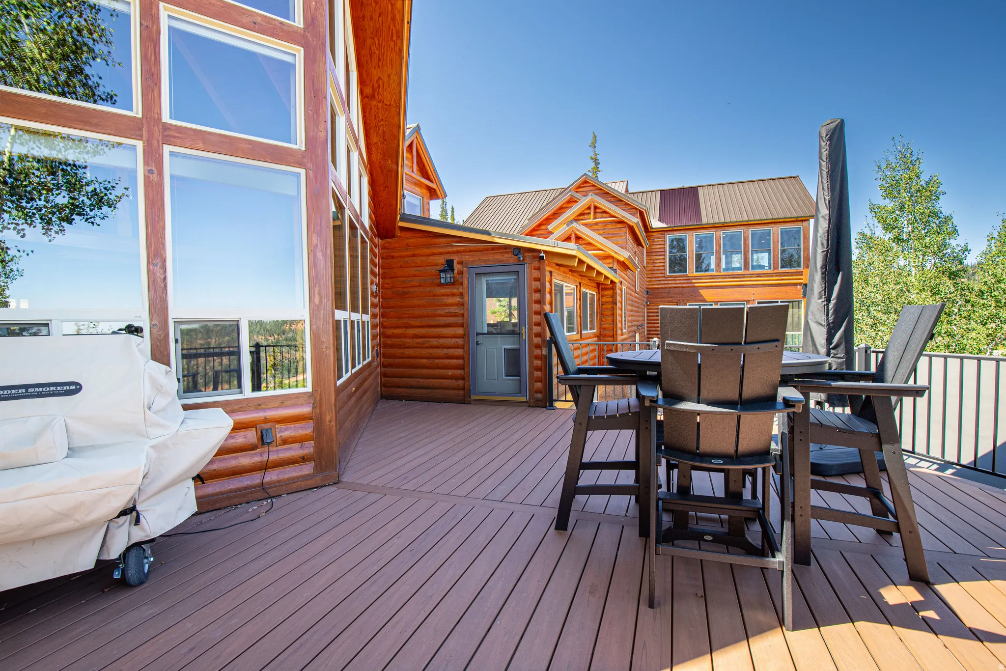 Expansive outdoor deck with composite decking, log-style exterior siding, and large picture windows