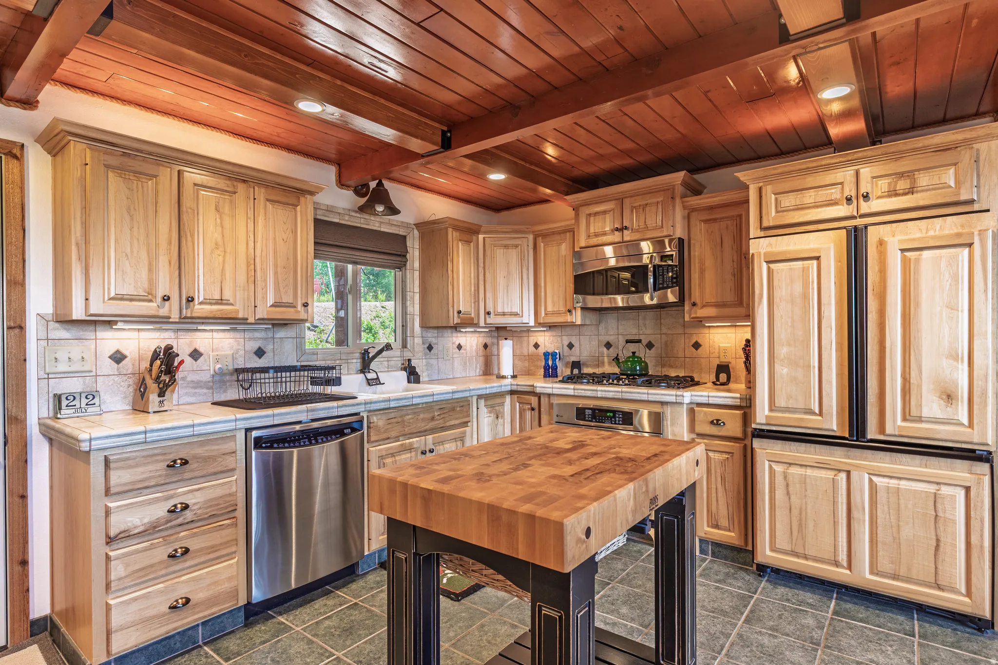 Kitchen featuring wood-paneled ceilings, natural wood cabinetry, stainless steel appliances, tile backsplash, and a butcher block island