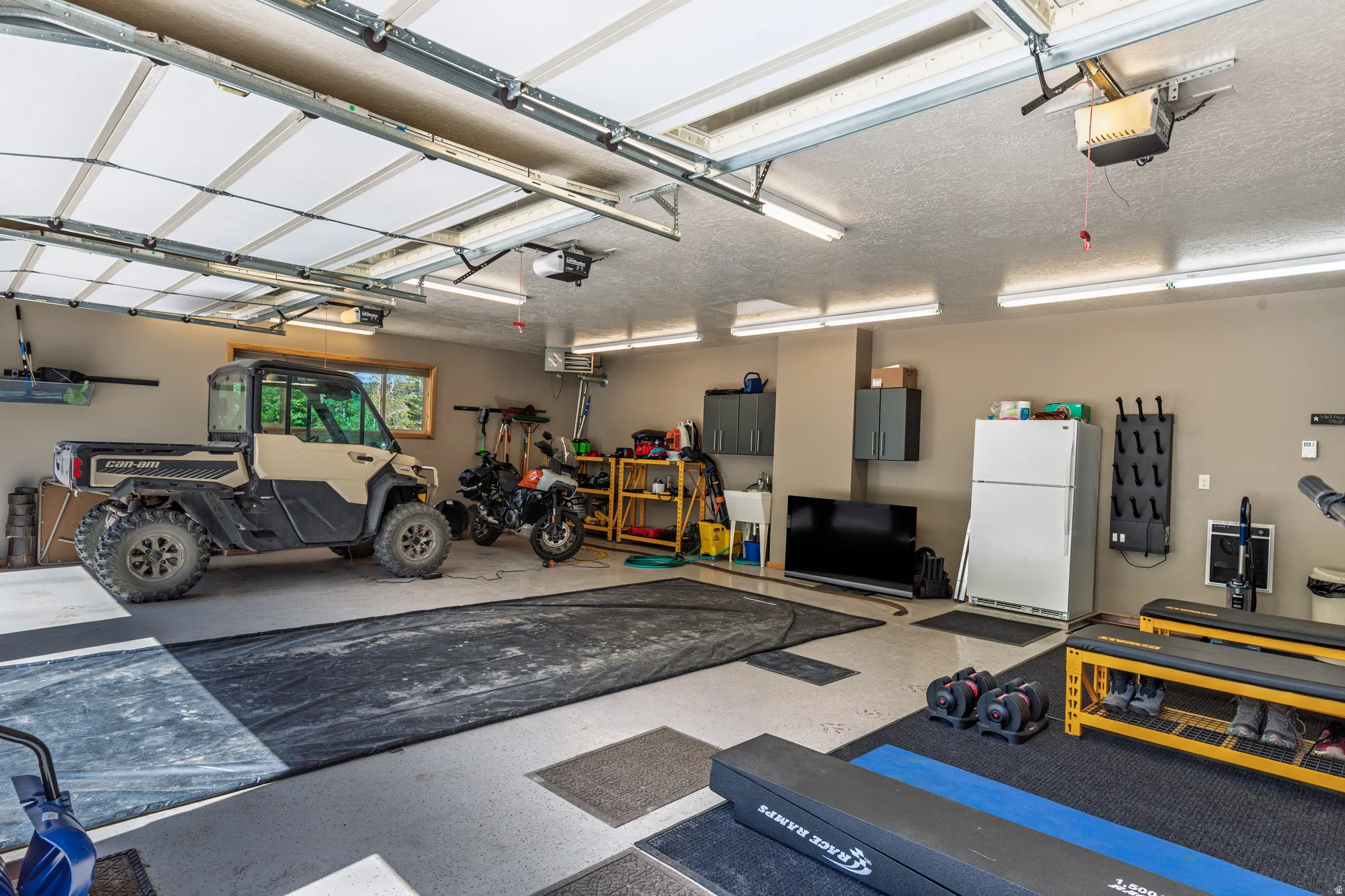 Three-car garage with overhead lighting, a utility sink, built-in cabinetry, and a window