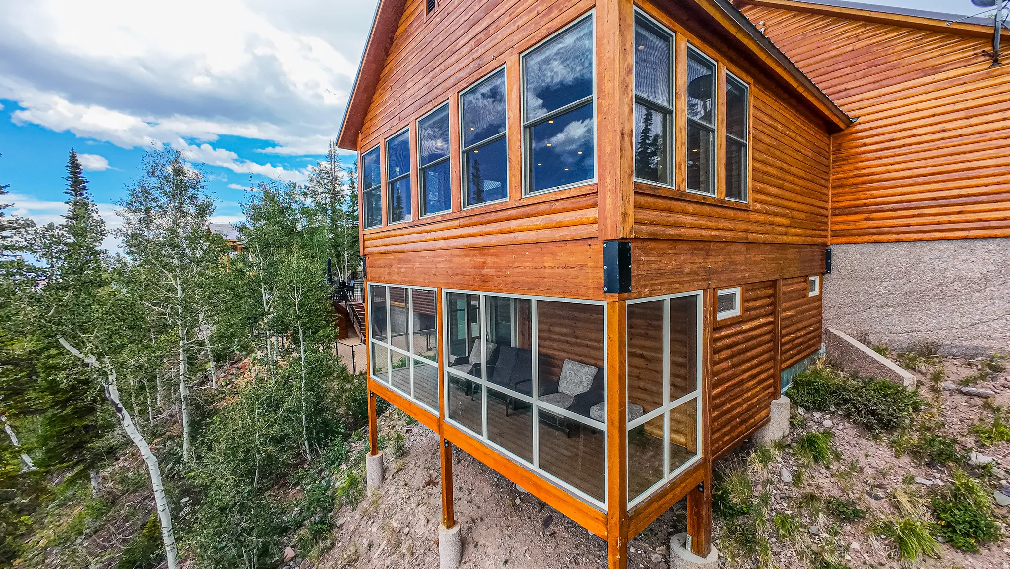 Wood-sided exterior featuring multiple large windows, a screened-in porch, and an upper-level sunroom