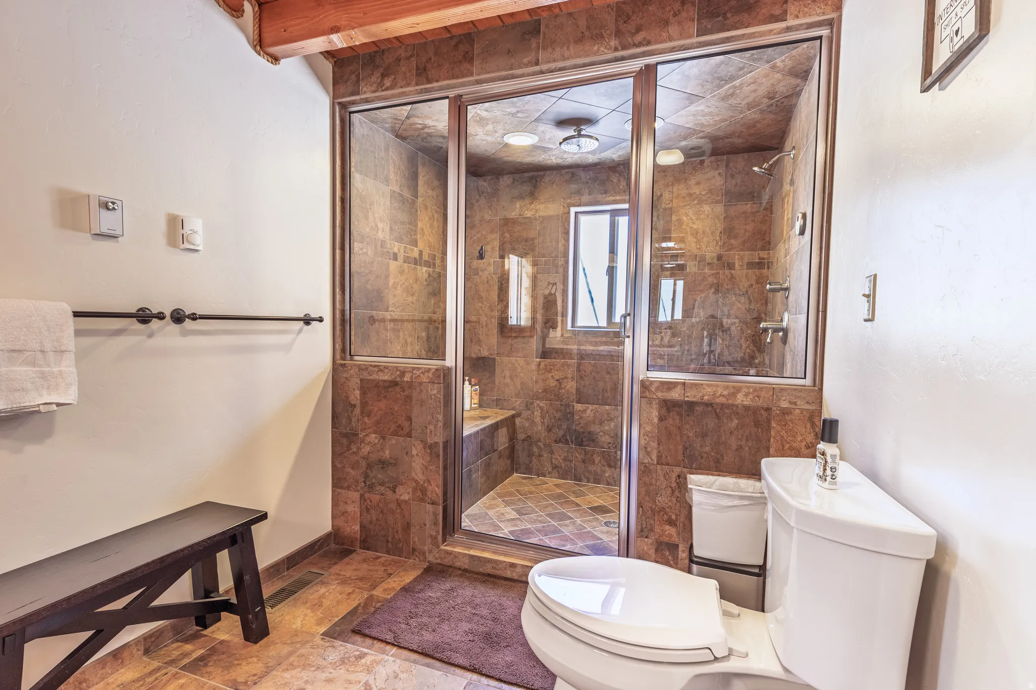 Glass-enclosed shower with full tile surround, integrated shower bench, and tile flooring