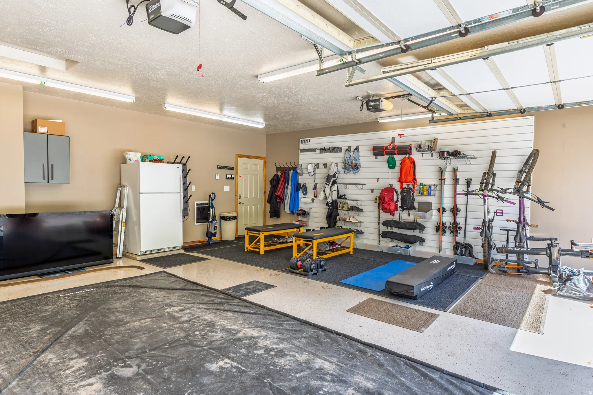 Garage featuring overhead lighting, light-toned walls, a white overhead garage door, and a utility door