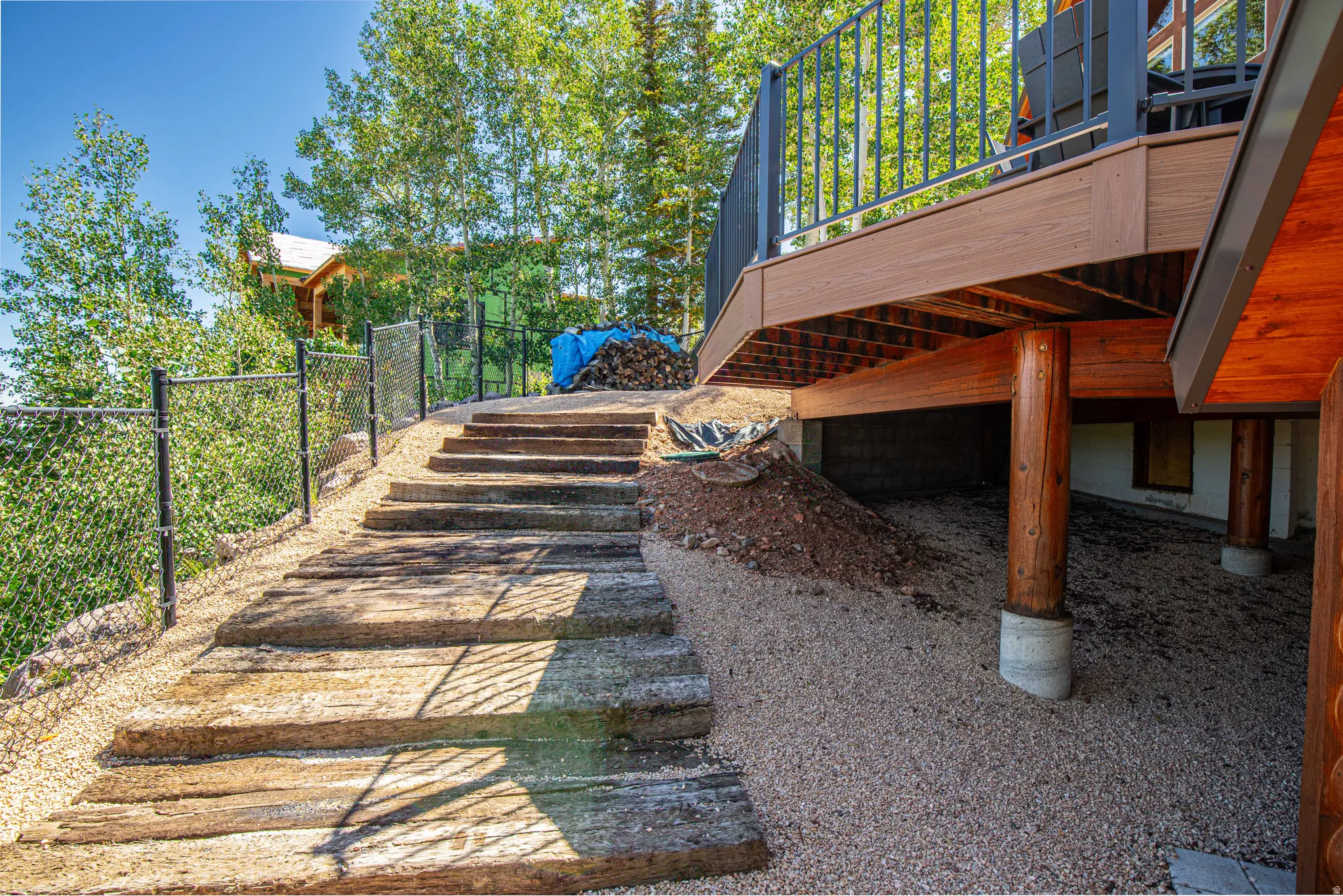 Multi-level outdoor decking with metal railings, supported by round timber posts