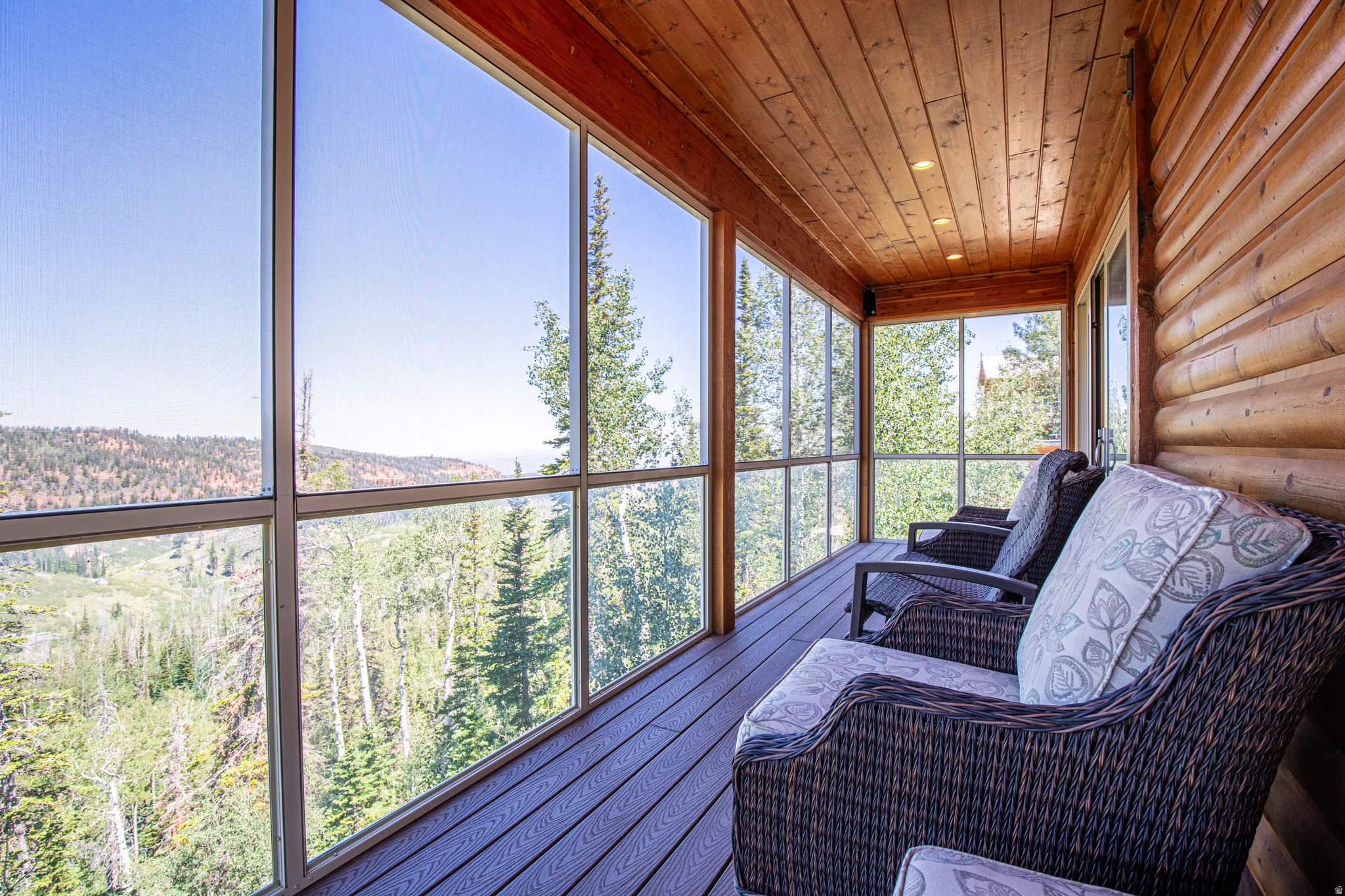 Screened-in porch featuring a plank wood ceiling, log wall construction, and expansive perimeter glass