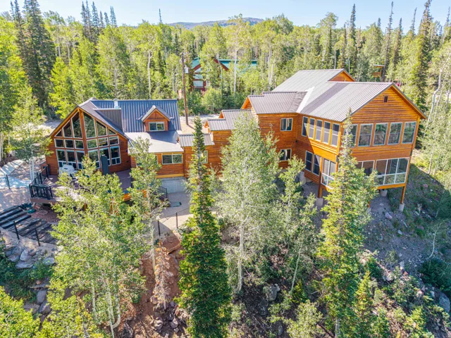 Wood-sided exterior featuring multiple gables, a metal roof, an expansive deck, and large windows