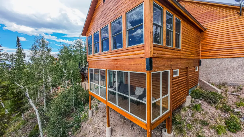 Wood-sided exterior featuring multiple large windows, a screened-in porch, and an upper-level sunroom