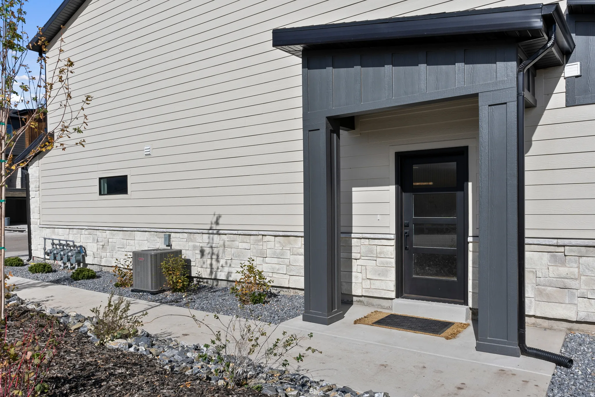 Entryway featuring a black paneled door with glass inserts, covered porch, and light-colored siding
