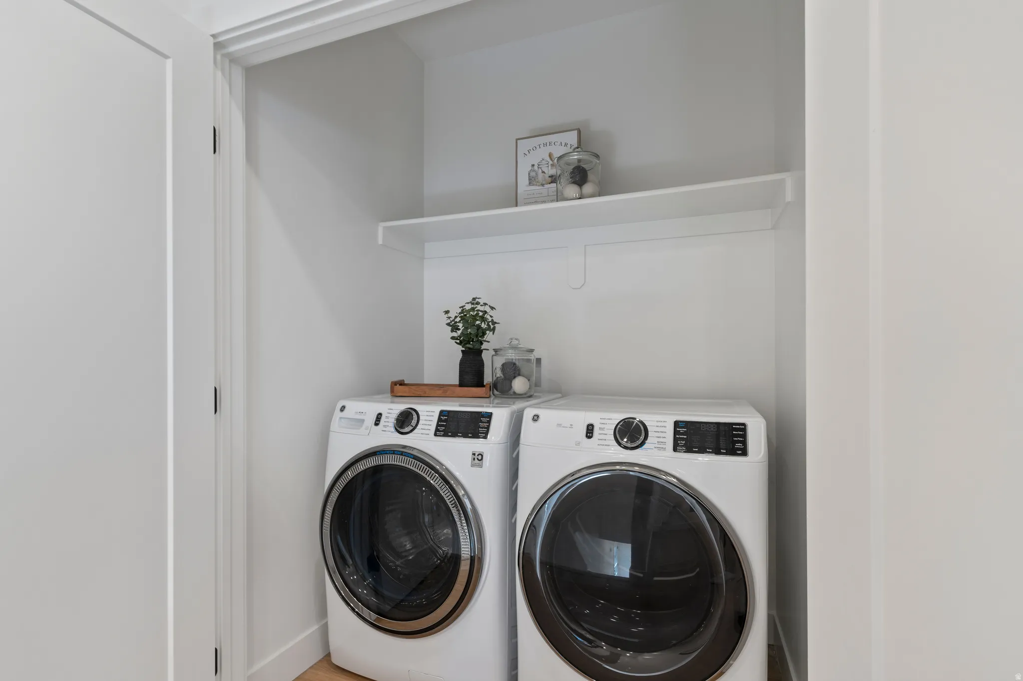 Laundry closet featuring a built-in shelf and light wood-finish flooring