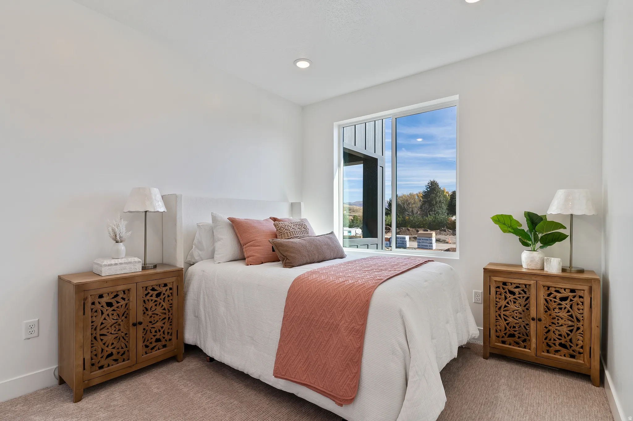 Recessed ceiling lighting, white walls, large window with exterior scenery, and light-colored carpeting