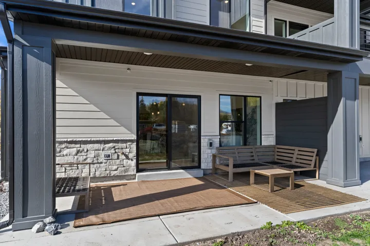 Covered patio featuring a sliding glass door, stone veneer detailing, and exterior siding