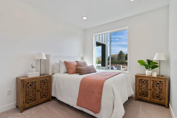 Recessed ceiling lighting, white walls, large window with exterior scenery, and light-colored carpeting