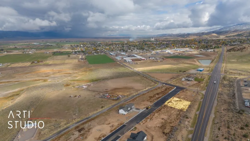 Expansive land parcel featuring a developing residential area, paved road access, and distant mountain scenery