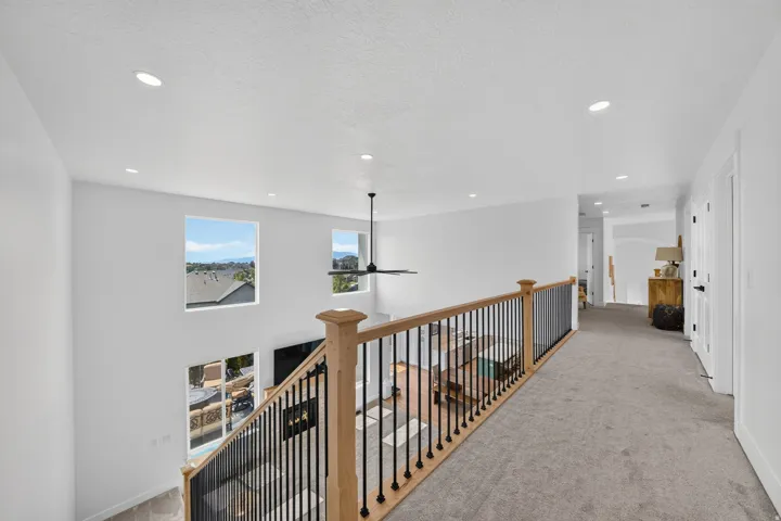 Upper-level hallway with neutral carpet flooring and recessed lighting