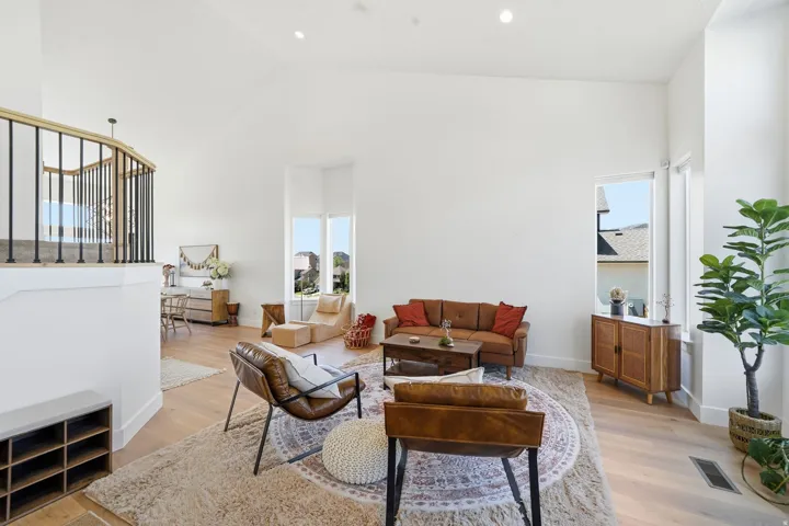 Vaulted ceilings with recessed lighting, wood-finish flooring, white walls, and a staircase with wood railing and black spindles