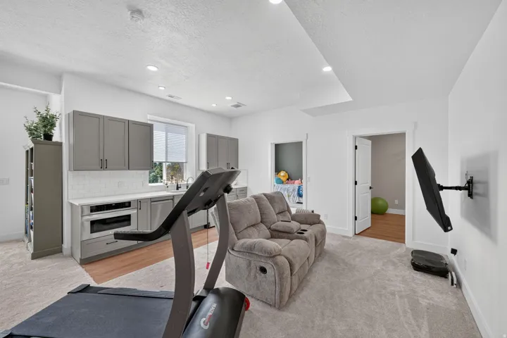 Integrated kitchenette featuring gray cabinetry, subway tile backsplash, and stainless steel appliances