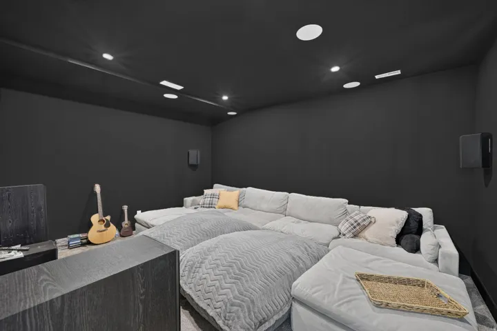 Built-in wall speakers, recessed ceiling lighting, and a dark wall finish create a dedicated media space