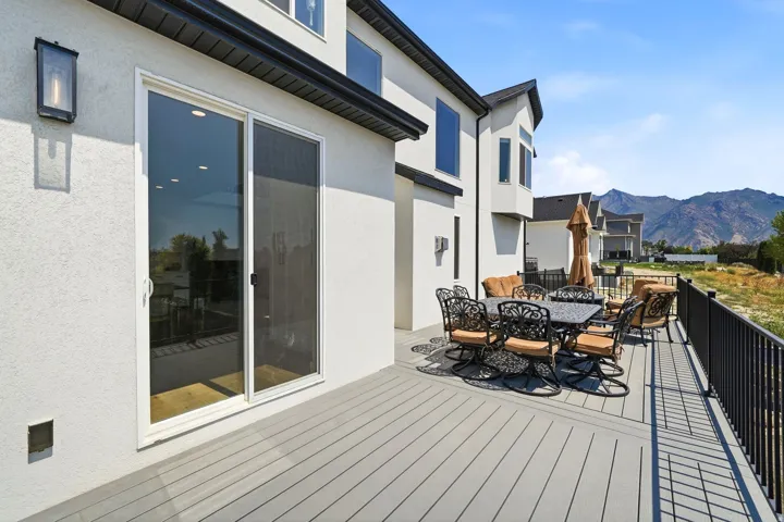Exterior deck with composite decking, black metal railings, and a sliding glass door