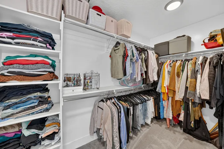 Custom closet system featuring multiple white shelving units and chrome hanging rods