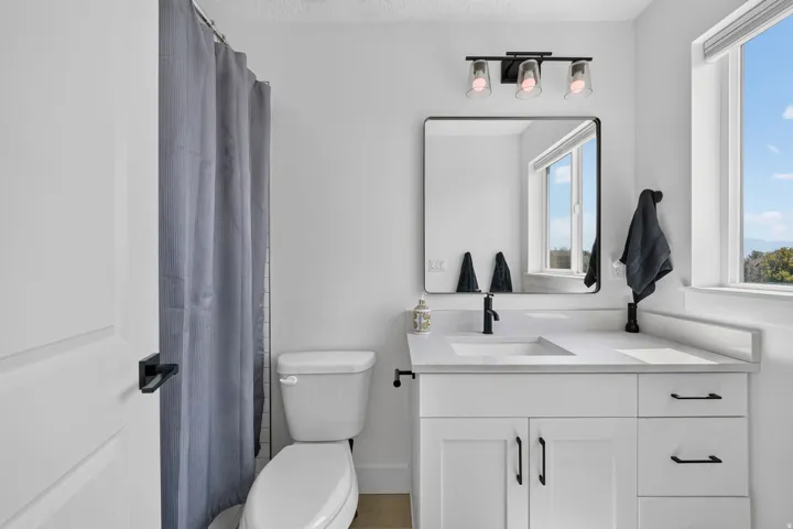 White vanity with a single basin, black faucet, and white countertop