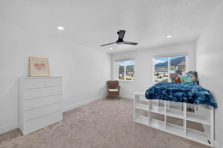 Recessed lighting, ceiling fan, white walls, two windows, and carpeting