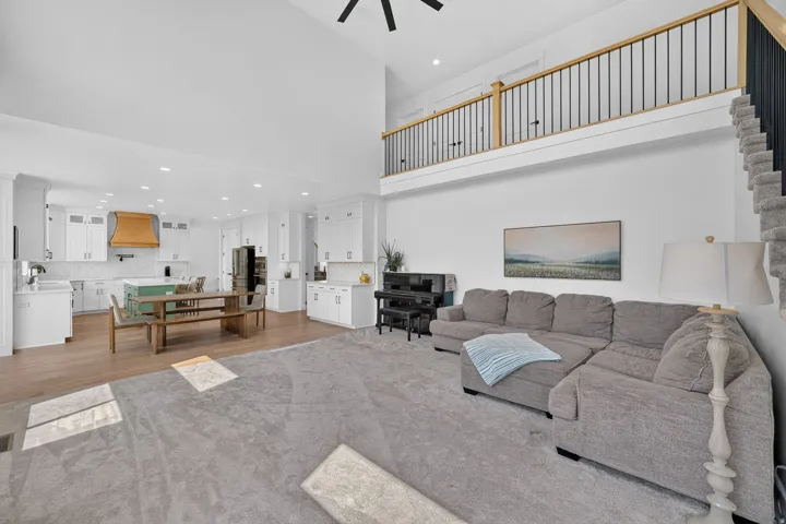 Open-concept living space with a vaulted ceiling, wood-finish flooring, and a second-story landing with wood and metal railings