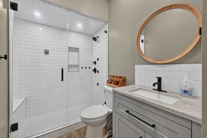 Walk-in shower with clear glass enclosure, subway tile surround, built-in shower bench, and recessed shower niche