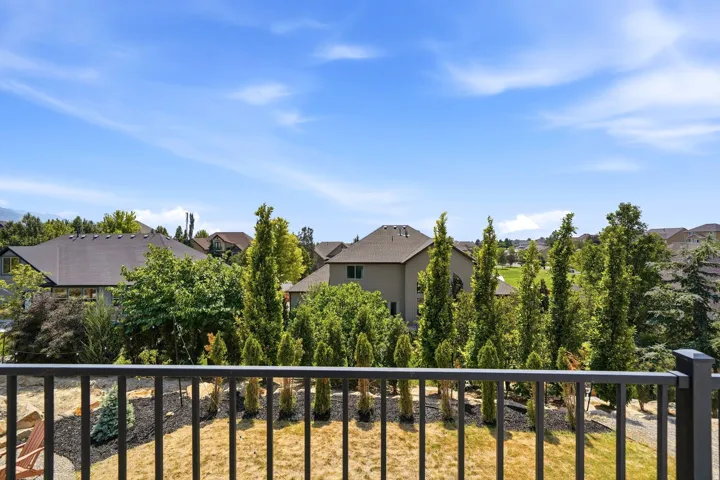 Black metal railing overlooking a residential area with mature trees and landscaping