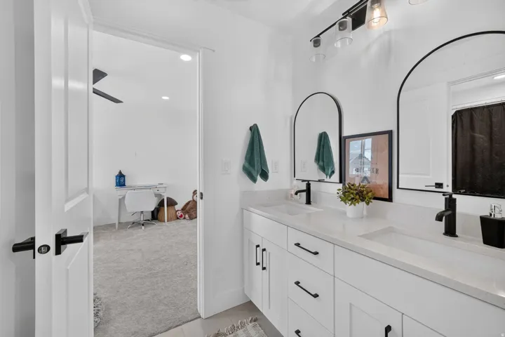 Dual arched mirrors over a spacious vanity with two undermount sinks and matte black fixtures