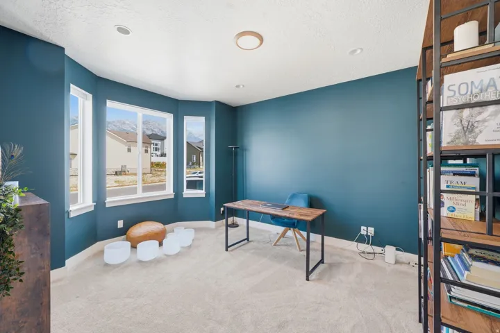 Recessed lighting, light-colored carpeting, large bay windows, mountain backdrop, and built-in shelving