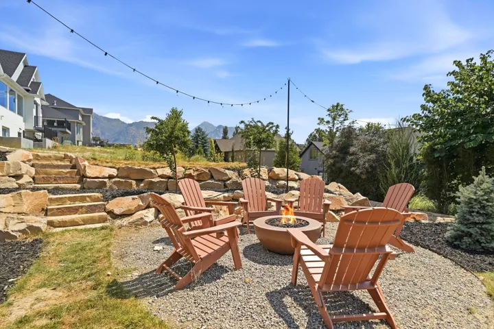 Outdoor fire pit feature on a gravel patio with string lighting