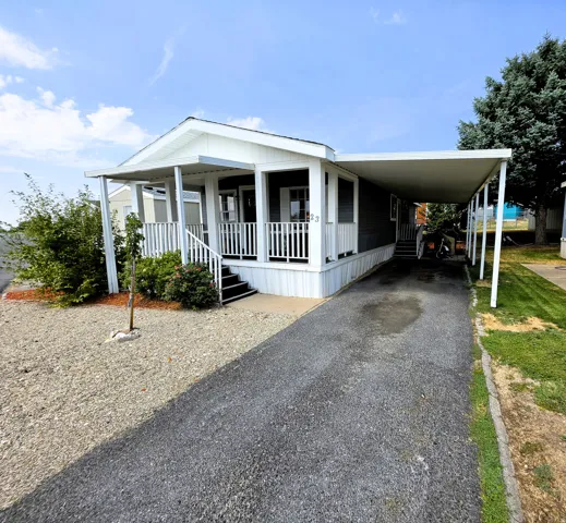 Covered porch with white railings and covered carport.