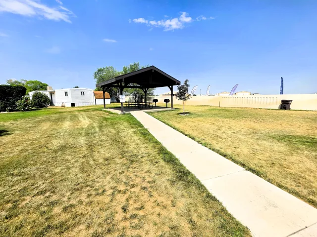 Expansive outdoor space featuring a covered picnic area, concrete pathway, and surrounding green areas