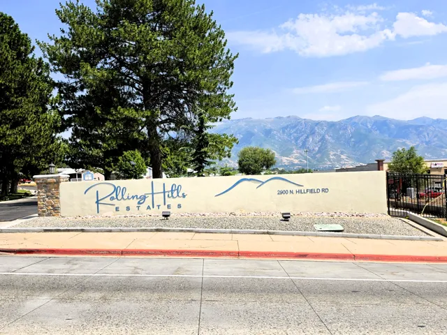 Entry monument featuring stone-clad pillars, stucco-finish wall, and integrated signage