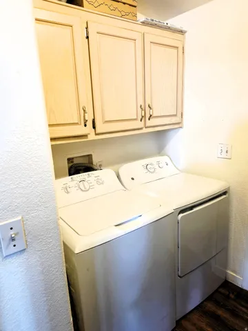 Overhead wood-finish cabinetry, laundry appliance hookups, and wood-finish flooring