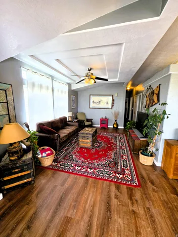 Wood-finish flooring, recessed ceiling with decorative trim, and an attached ceiling fan with lighting