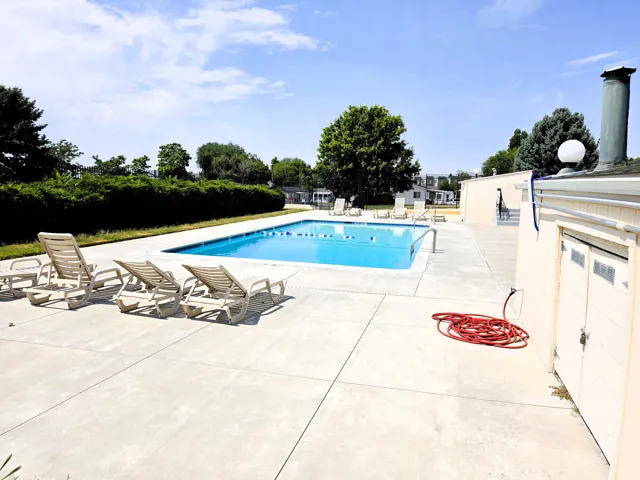 Community outdoor swimming pool featuring a large concrete deck