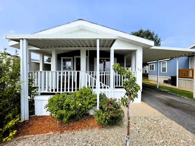 Covered front porch with white railings, and an attached carport