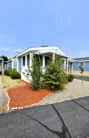 Blue siding exterior with white trim, covered front porch, gravel landscaping, and red bark mulch