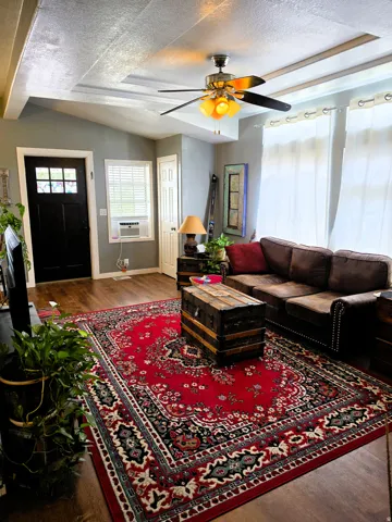 Wood-finish flooring, ceiling fan with integrated lighting, and a paneled entry door with decorative glass inserts