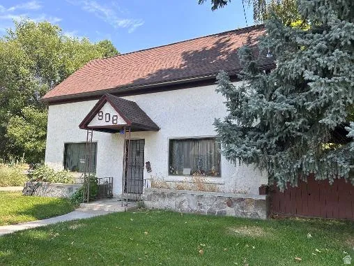 Stucco exterior with a peaked entry awning, stone foundation details, and a brown shingle roof