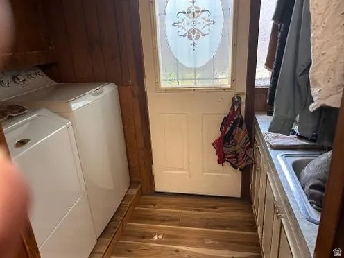 Wood-finish flooring with wood-paneled walls, utility sink, and built-in cabinetry