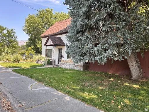 Stucco exterior with a peaked roof, covered entry, and a stone foundation accent