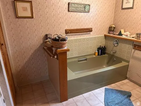 Built-in bathtub with chrome fixtures, surrounded by patterned wall tile