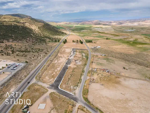 Expansive undeveloped land featuring a paved roadway, mountainous terrain, and distant water features