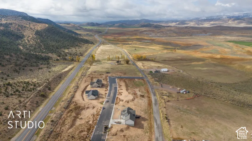 Newly developed residential lots with paved streets, surrounded by expansive natural landscapes and distant mountains