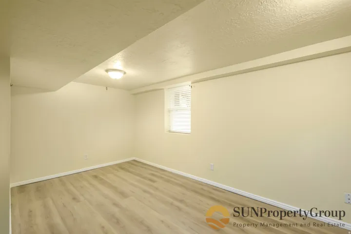 Recessed window with blinds, wood-finish flooring, and flush mount ceiling light