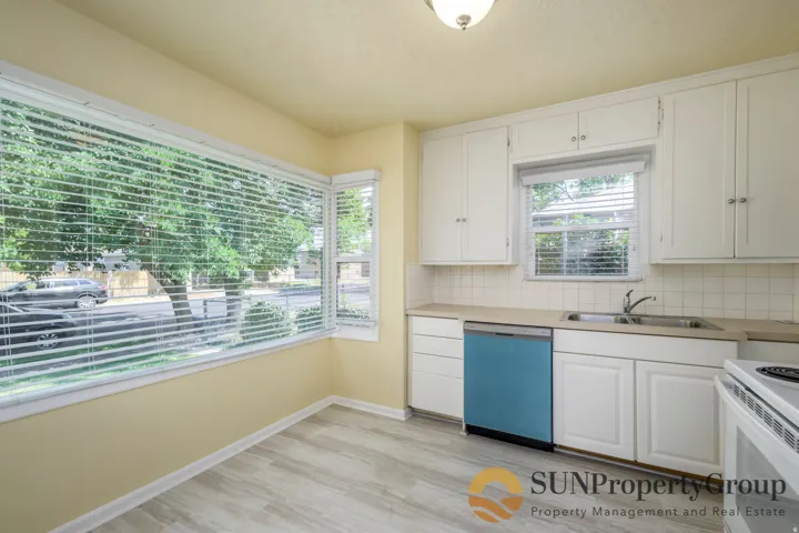 White cabinetry and a tile backsplash complement the wood-finish flooring