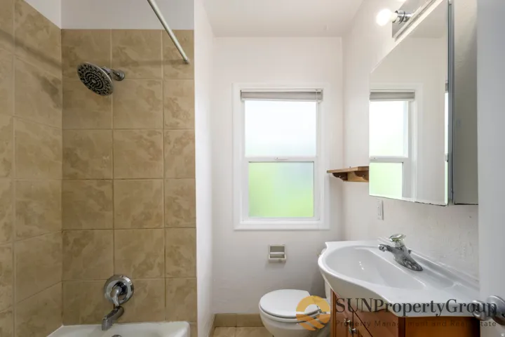 Bathroom featuring a tiled shower surround, a single vanity with storage, and an overhead light fixture