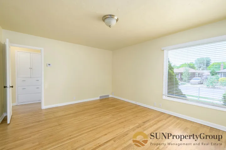 Hardwood flooring, large picture window with blinds, built-in cabinetry, and a flush mount ceiling light