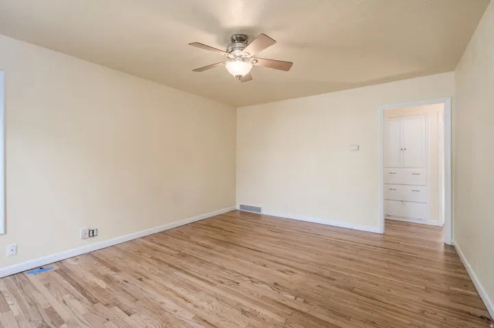 Hardwood flooring, ceiling fan with integrated lighting, built-in cabinetry, and wall-mounted electrical outlets